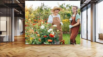 Teenager grandchild helping to her elderly grandmother at the garden in summer outside. Granddaughter and her pensioner senior granny working together at countryside. Wall mural