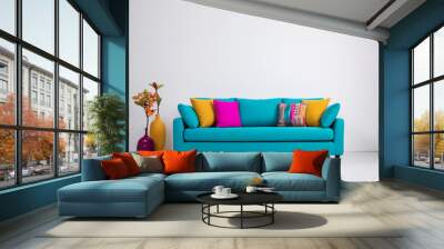 Turquoise sofa with colorful cushions near a blank white wall. Modern interior for mockup, wall art. Promotion background with copyspace. Wall mural