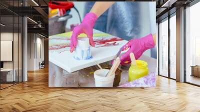 Woman painter creating fluid acrylic abstract painting in art therapy class, dropping paints on canvas. Wall mural