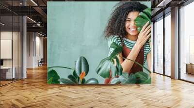 Young woman with natural make up and tropical monstera leaf in hand over green background with copy space. Skin care, pure beauty, body treatment, cosmetics concept. Wall mural