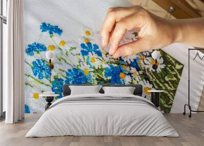 embroidery process close-up. female hand embroiders a floral ornament with a needle. hobby and needlework concept Wall mural