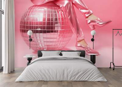 Doll legs in pink shoes and silk trousers with disco ball on pink background. Wall mural