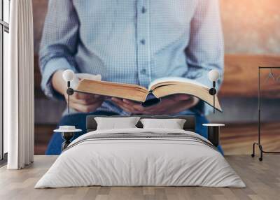 a man sit on wooden chair and reading bible or book over concrete wall with window light Wall mural