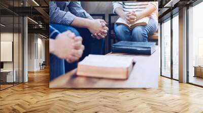 Christian group are praying together around wooden table with holy bible Wall mural