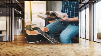 close up of a man hands holding  and read book  with guitar on wooden table, christian background, devotional concept Wall mural