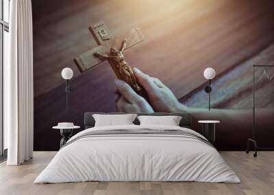 Close up of woman hands holding crucifix of Jesus Christ while praying to God on wooden table background, Christian trust and faith concept with copy space. Wall mural