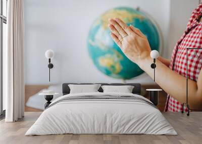 Close up of woman hands praying over blurred world globe and bible on wooden table with white wall background, christian world mission concept, Copy space Wall mural