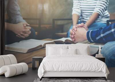 group of christian  sitting around wooden table with open blurred bible page and praying to God together Wall mural