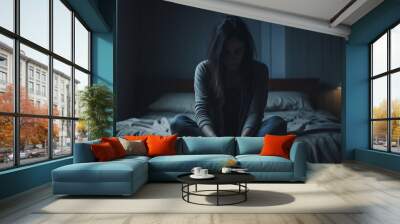 Young woman is sitting in an empty bed in a dark bedroom Wall mural