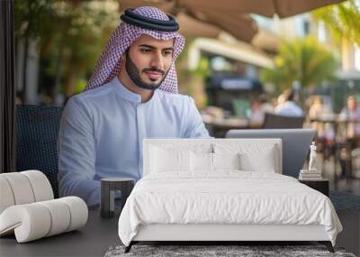 Arabic businessman sitting in outdoor restaurant working online with laptop computer. Middle eastern man business manager Wall mural