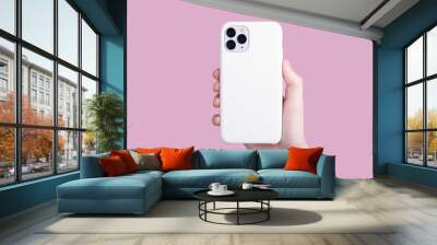 Female hand holding white iPhone 11 Pro in soft silicone white cover back view . Phone case mock up isolated on pink background , iPhone 12 Wall mural