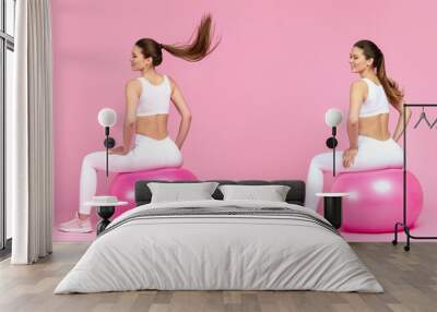 Happy young athletic woman jumping on barbie pink fit ball during fitness workout wearing white tracksuit isolated on pink background, full length photo back view, two girls in motion collage banner Wall mural