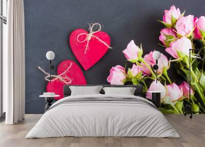 Small pink roses and two wooden red hearts on a dark gray background. Valentine's day composition, selective focus. Wall mural