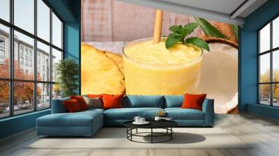 pineapple coconut smoothie with a bamboo straw and a mint leaf on top. on the side pineapple slices and two coconuts. stone surface and white wooden planks background. copy space for advertising. Wall mural