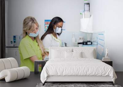 two dentists doctors in the sterilization room of a dental clinic. They are working sterilizing the material Wall mural