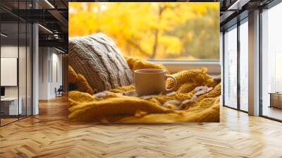 A cozy autumn scene with yellow blankets and a cup of coffee on an armchair by the window, inviting warmth for fall relaxation Wall mural