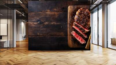 Sliced medium-rare beef steak on a dark wooden table with copy space, top view. Gourmet meat dinner background. Black slate plate and fork. BBQ grill food concept. Top-down view. Wall mural