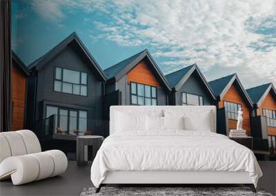 Modern row of houses with orange and black siding, balconies and cloudy sky. Wall mural