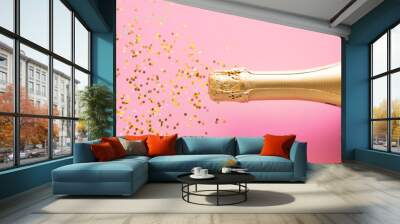 a bottle of champagne and a scattering of confetti. Christmas firecracker concept on pink background Wall mural