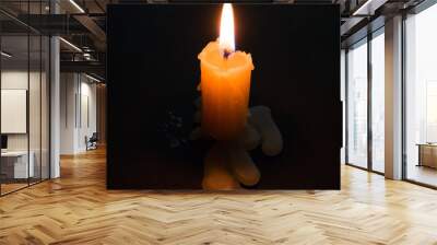 Burning candle with melting wax close-up on a black background Wall mural