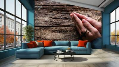 man praying with a cross in his hands on a wooden background Wall mural