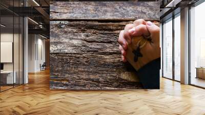 man praying with a cross in his hands on the wooden background with space for text Wall mural