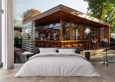 A large wooden building with a glass roof and a patio area with wooden tables Wall mural