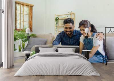 Happy indian Couple Using Laptop Browsing Internet Together on sofa at home Wall mural