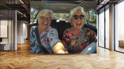 Smiling older woman and friend driving car on the way to travel on summer Wall mural