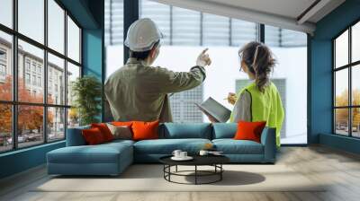 Two professional engineer and architect in safety helmet working together at construction site Wall mural