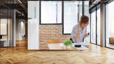 woman celebrating success or promotion bonus while working on laptop Wall mural