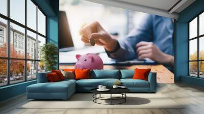 Young woman putting a coin inside piggy bank as savings for investment. wealth and financial concept. Wall mural