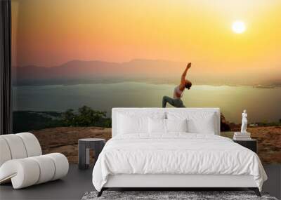 Woman practice yoga on mountain with sunset or sunrise background Wall mural