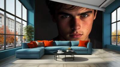 Artistic headshot of a young man with dramatic lighting and a serious expression Wall mural