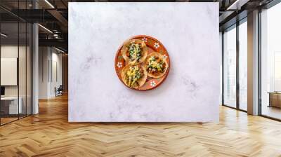 Mexican tacos served, top view of taco served on blue ceramic plate near bowls of salsa sauce and chopped greens and onion placed on wooden table with drink Wall mural