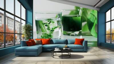 Chlorophyll extract is poured in pure water in glass against a white grey background with green leaf. Liquid chlorophyll in a glass of water. Concept of superfood, healthy eating, detox and diet Wall mural