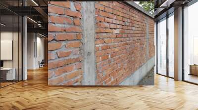 Brick wall made of bright red bricks around a catholic cemetery. The fence is 2 meters high. Cement between the rows. Grunge background. Facing the facade. Fence made of anti-vandal material. Asphalt Wall mural