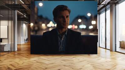 Contemplative man wearing suit sits alone dimly lit urban setting. Man in formal attire reflects quietly as he sits alone, gazing thoughtfully into distance amidst softly illuminated evening backdrop Wall mural