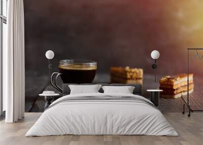 glass cup of black coffee and two caramel nut cake slices on wooden table. dark food photography Wall mural