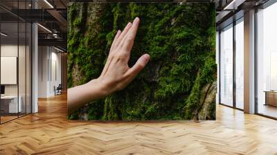 Girl hand touches a tree with moss in the wild forest. Forest ecology. Wild nature, wild life. Earth Day. Traveler girl in a beautiful green forest. Conservation, ecology, environment concept
 Wall mural