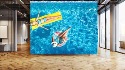 Aerial drone view of children in swimming pool from above, happy kids swim on inflatable ring donut and mattress, girls have fun in water on family vacation on holiday resort
 Wall mural