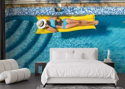 Beautiful young girl relaxing in swimming pool, woman swims on inflatable mattress and has fun in water on family vacation, tropical holiday resort, aerial drone view from above
 Wall mural