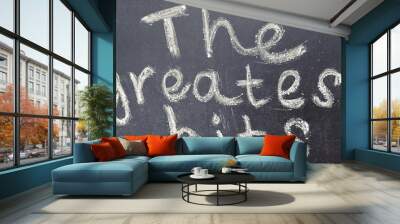 The phrase The greatest hits is handwritten in white chalk on a black blackboard Wall mural