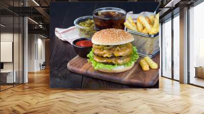 Cheese burger with two beef patty, cheddar cheese, lettuce, caramelized onion and jalapeno slices, served with french fries and soda, on a wooden board, horizontal, copy space Wall mural