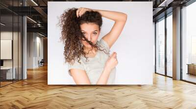 Beautiful and pretty young woman playing with hair and looking at the camera Wall mural