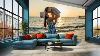 Beautiful young mother kiss daughter at the sea sunset and beach background. Happy family vacation. Travel. Caucasian happy female with baby outside at ocean sunset. Motherhood love care. Silhouette Wall mural