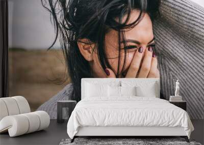 Closeup cropped portrait of happy and funny brunette woman smiling and laughing with hand on mouth, against nature meadow background with windy hair. People, travel and lifestyle concept. Cover mood. Wall mural