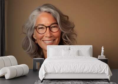 Smiling woman with gray hair and glasses, wearing a patterned top, against a beige background. Wall mural