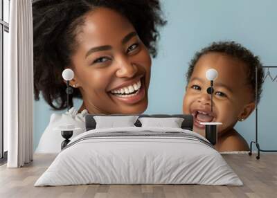 Tender studio photo of an African American mother and her happy baby, showcasing their close relationship and mutual affection. Wall mural