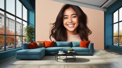 The embodiment of youthful happiness, a teenage girl grins from ear to ear against a serene studio backdrop. Wall mural